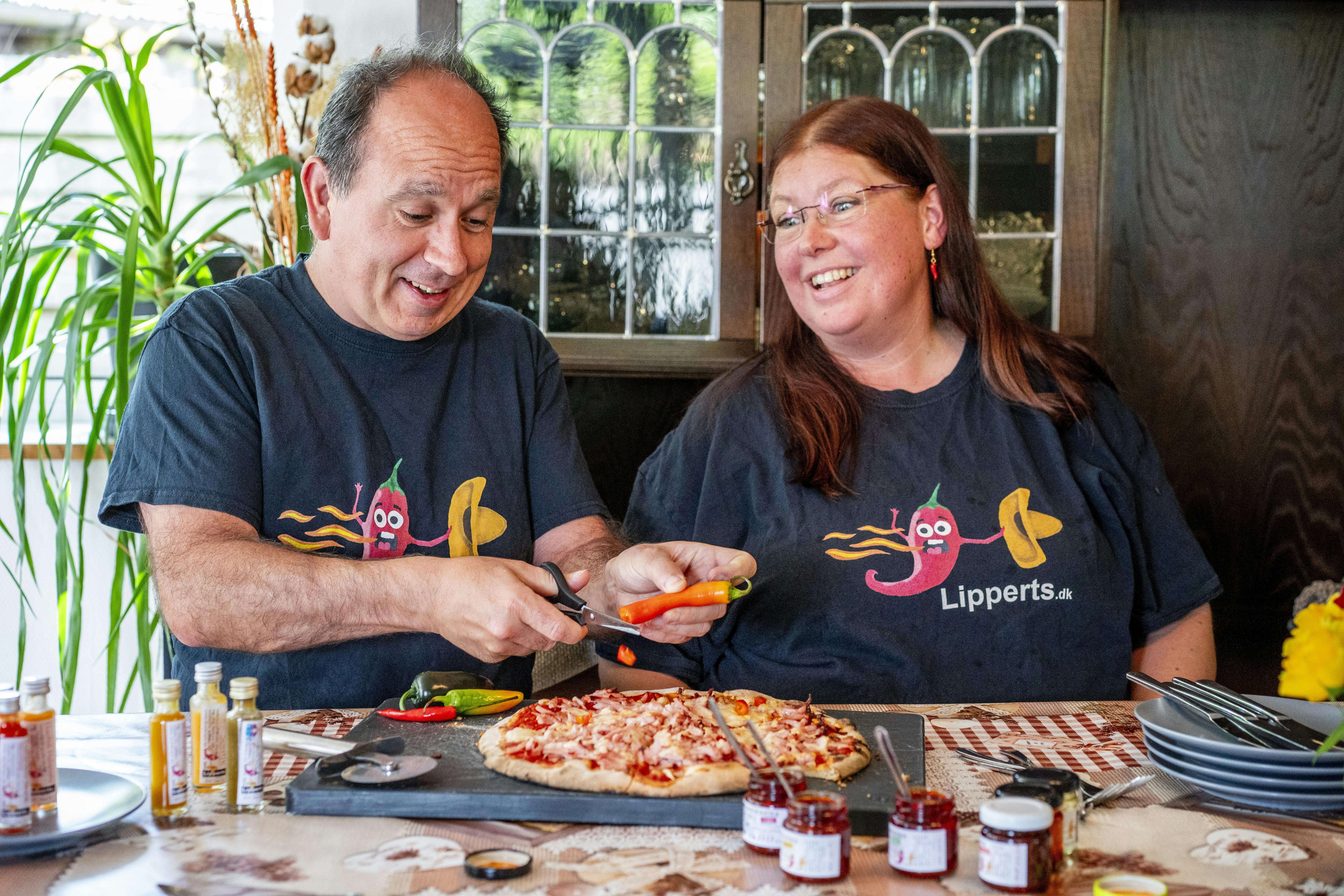 Annika og Tonny Lippert spiser pizza, der krydres med et udvalg af specialiteter fra deres firma, Lipperts Landbod.